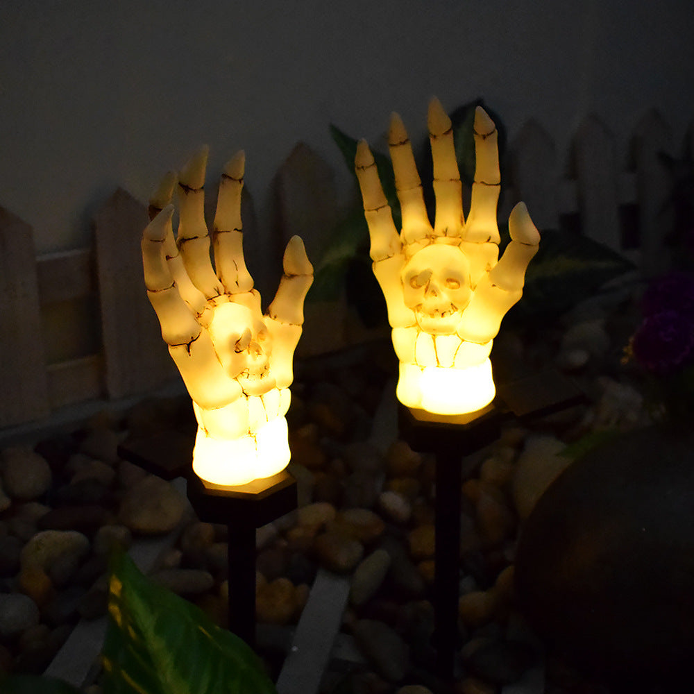 Close view of two lit skeleton hands, with the skull moulded into each palm