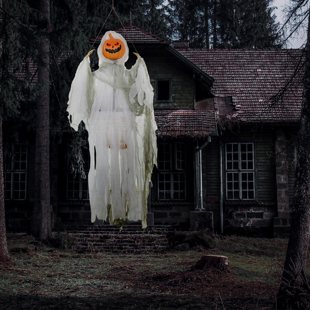 Hanging pumpkin-ghost prop suspended in front of a dark house