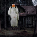 Hanging pumpkin-ghost prop suspended in front of a dark house