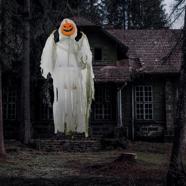 Hanging pumpkin-ghost prop suspended in front of a dark house