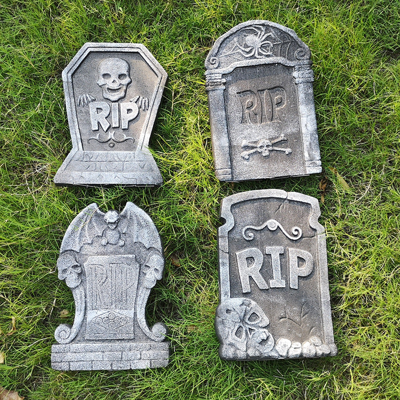 The four foam tombstone designs laid flat on grass: skull RIP, spider RIP, gargoyle, and RIP with skulls