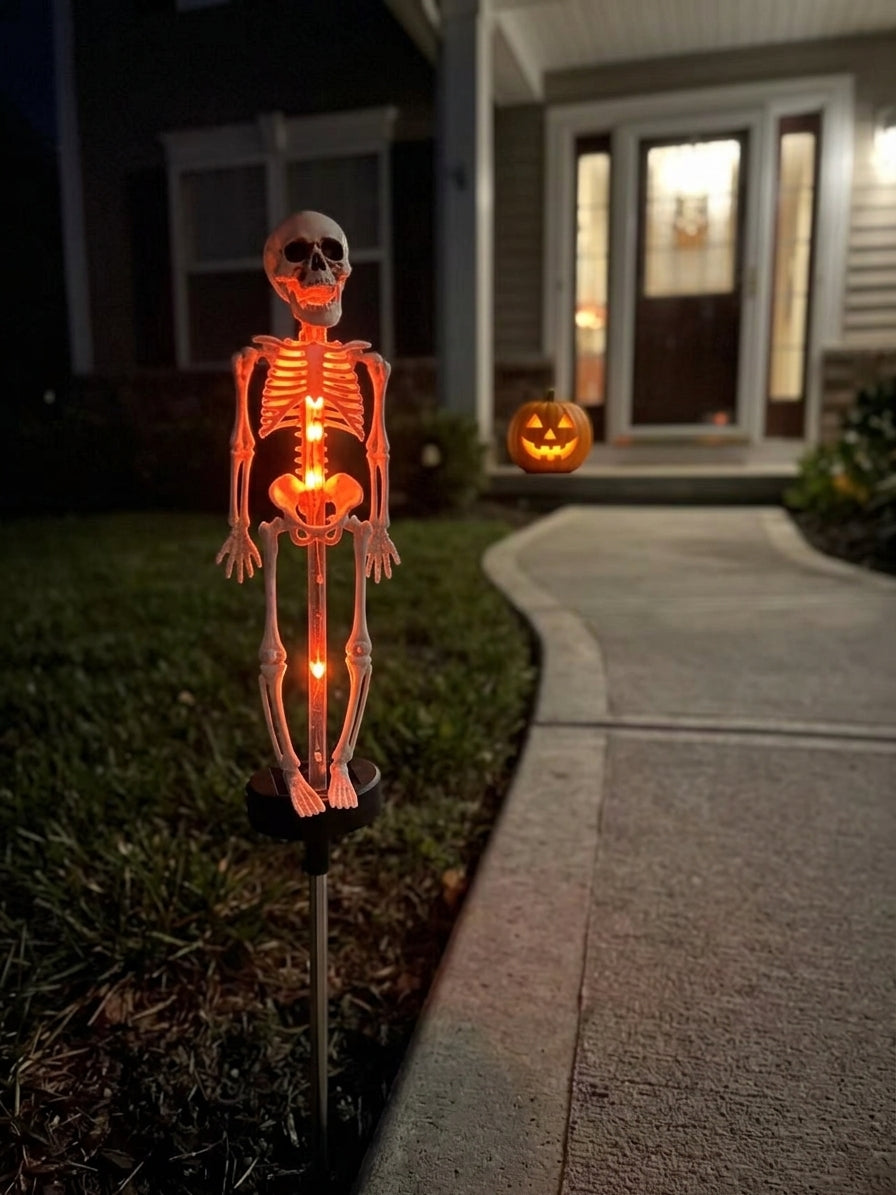 The skull lamp glowing orange beside a front walk at night