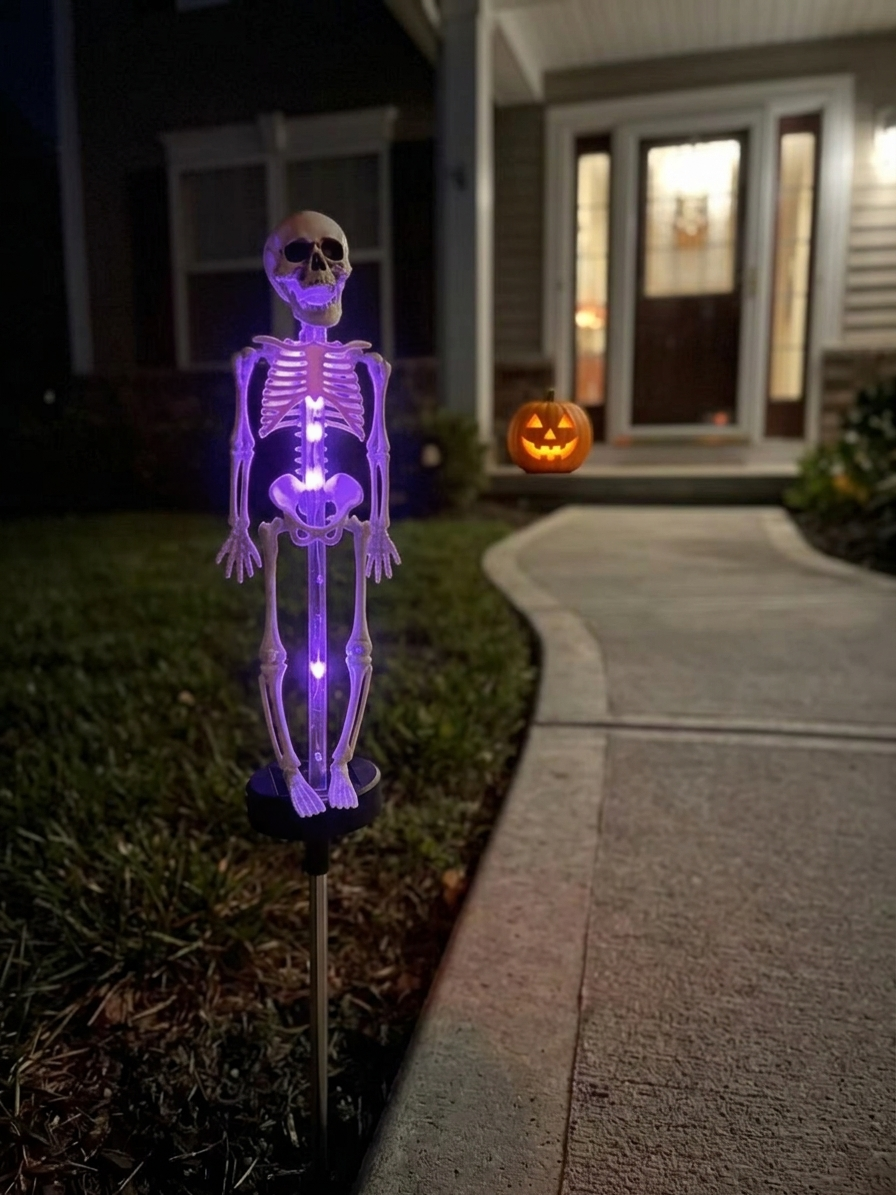 Solar skull lamp with a purple glow beside a front walk at night