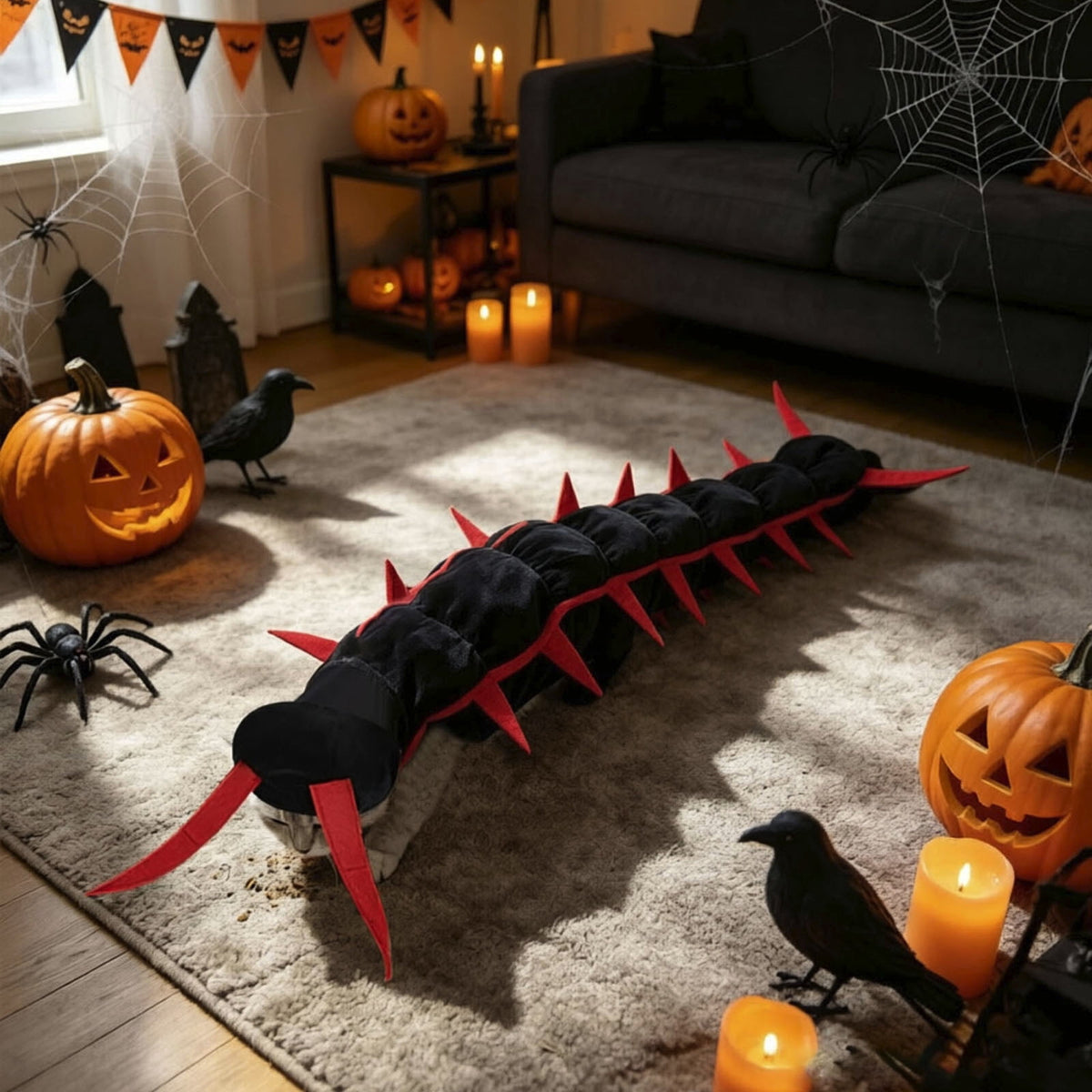 The centipede costume on a rug beside carved pumpkins, showing its full 50-inch length